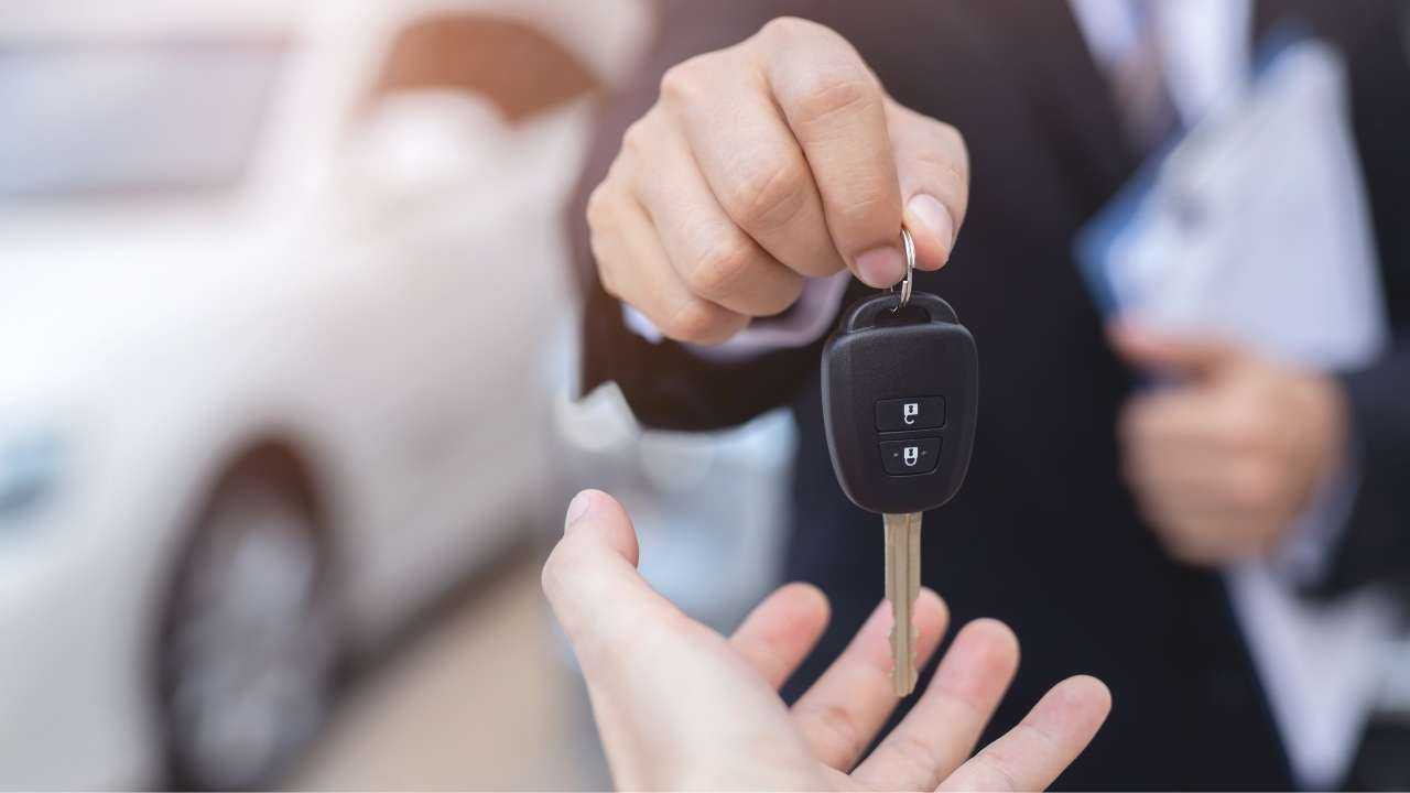 Viens cilvēks otram dod atslēgu no mašīnas, kas iegādāta pateicoties auto kredītam