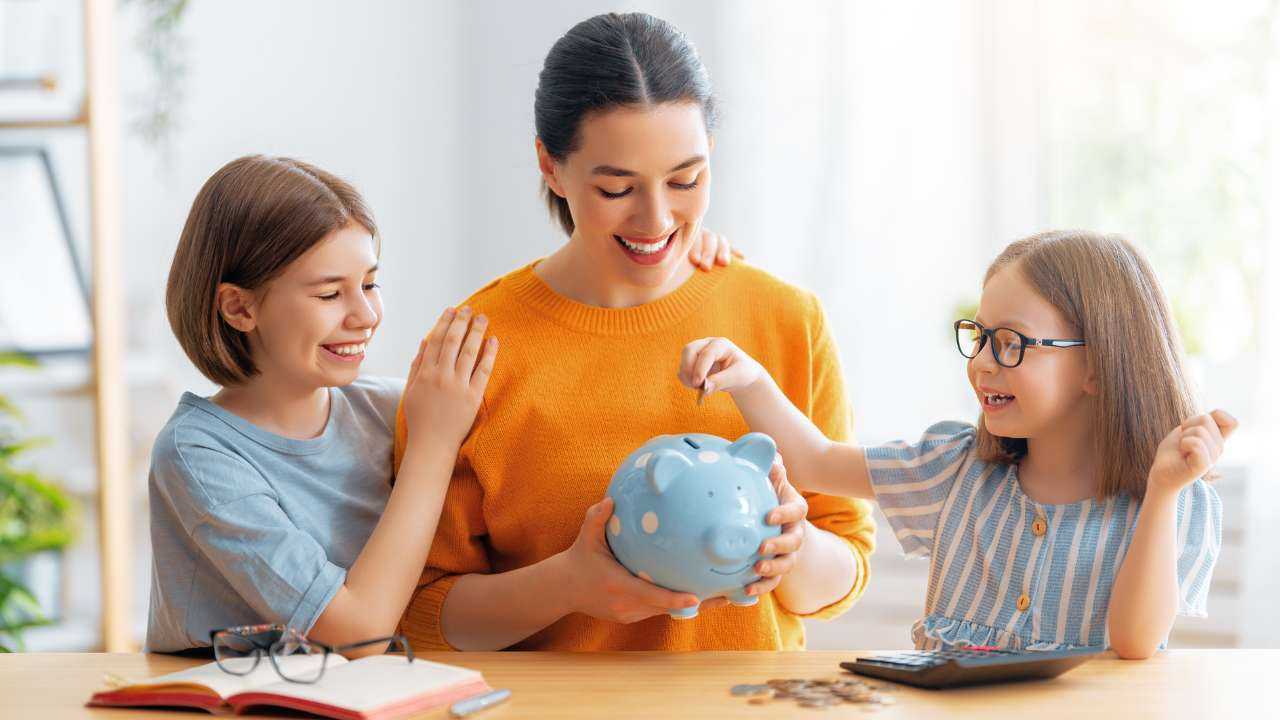 Māte ar savām meitām liek naudu krājkasītē un stāstā par finanšu gudrībām, kas noderēs dzīvē