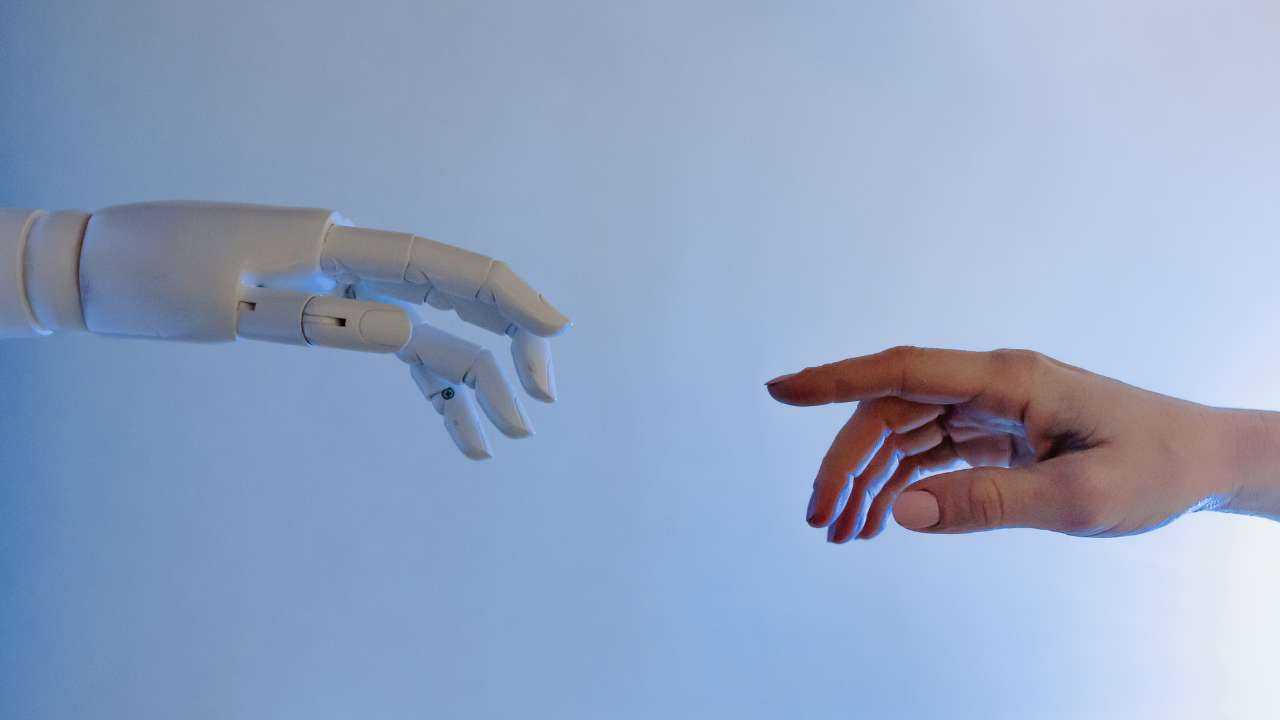 На голубом фоне две руки, одна робо-консультанта и вторая человеческая, тянутся к друг к другу, чтобы соприкоснуться