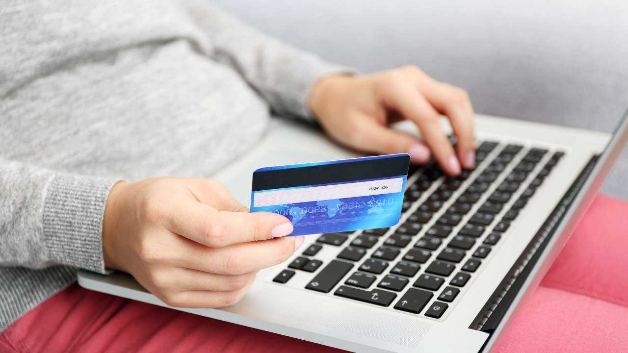 Sieviete, ērti sēžot un turot bankas karti, mēģina internetā pieteikties kredītam, jo uzzināja noderīgus ieteikumus aizņēmuma noformēšanai
