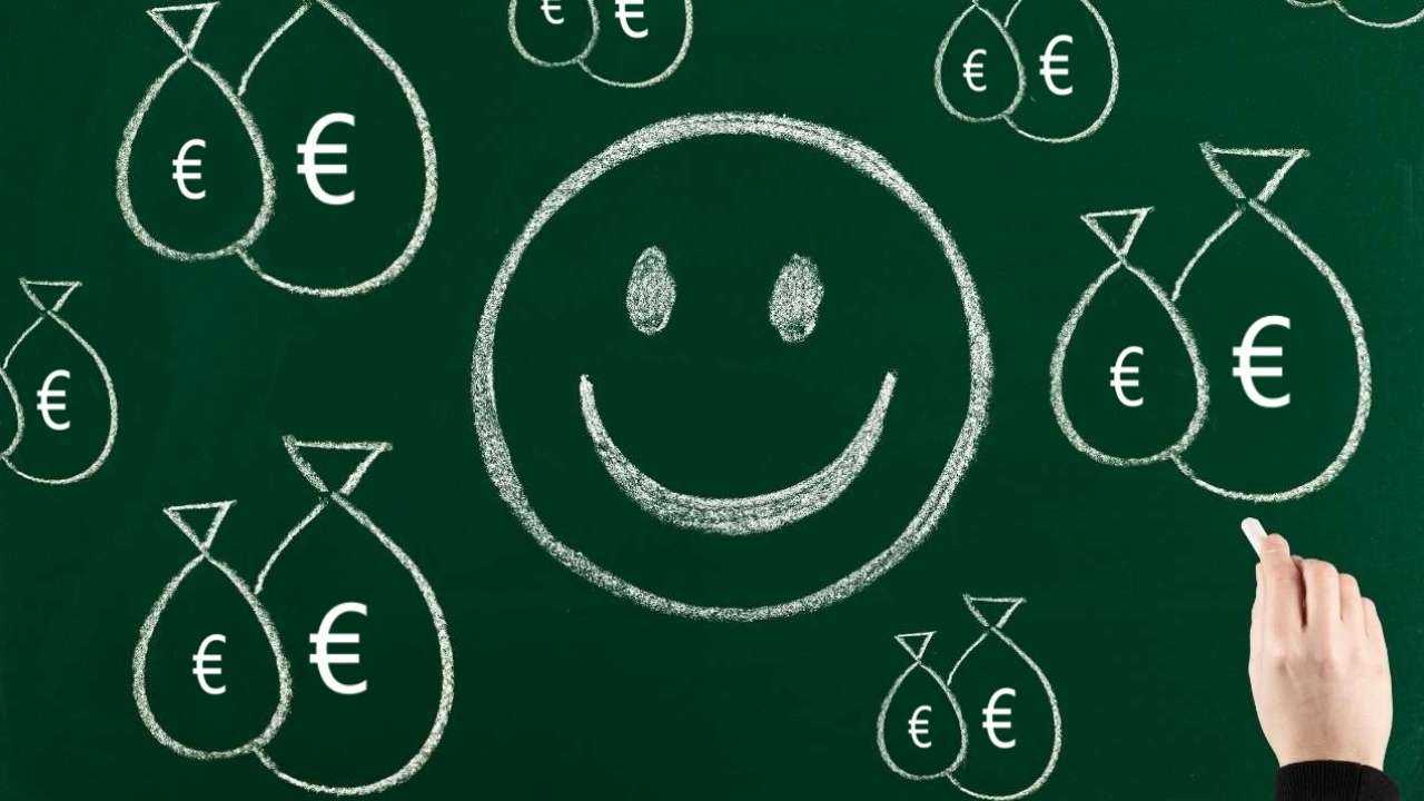 Uz tāfeles uzzīmēti naudas maisiņi ar eiro simboliem un smaidiņš, jo laimi var nopirkt par naudu