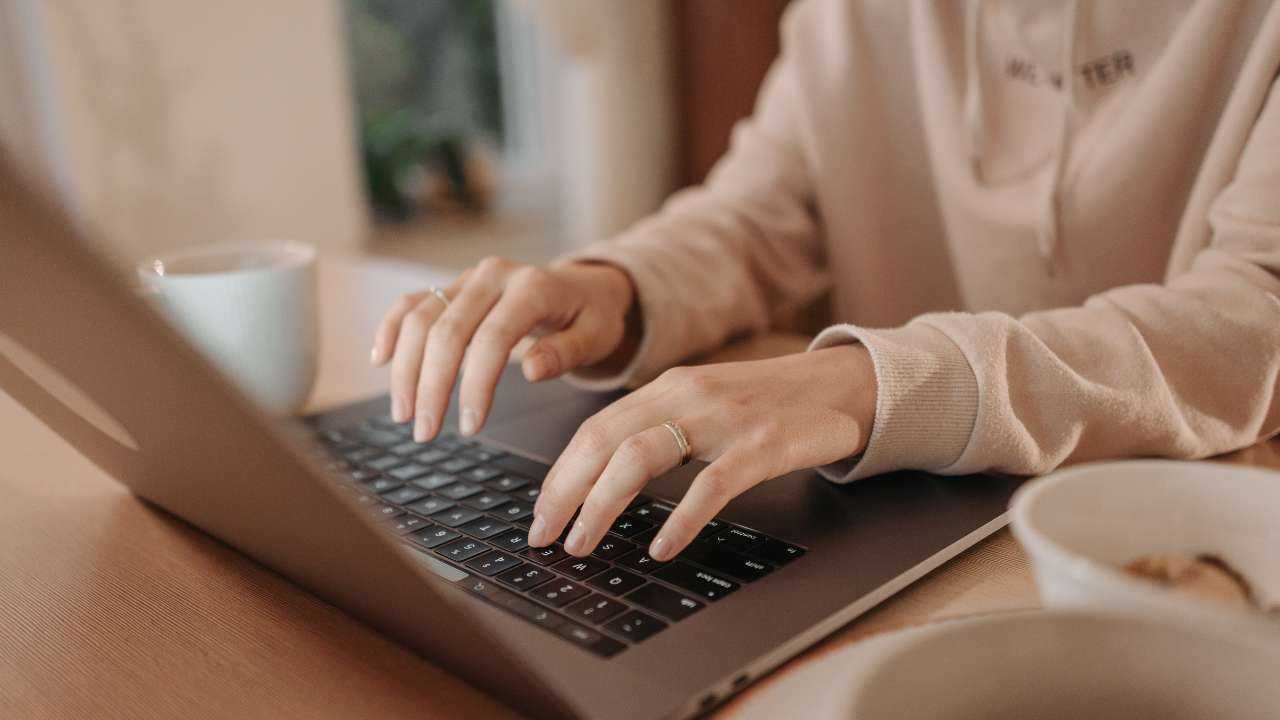Женщина за утреннем кофе в ноутбуке ищет, где доступны кредиты онлайн