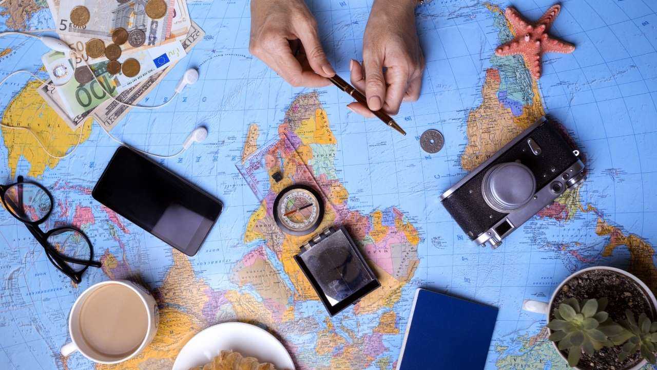 Galds ar pasaules karti un priekšmetiem ērtākai ceļojuma plānošanai un izvērtēšanai, kur paņemt kredītu ceļojumam
