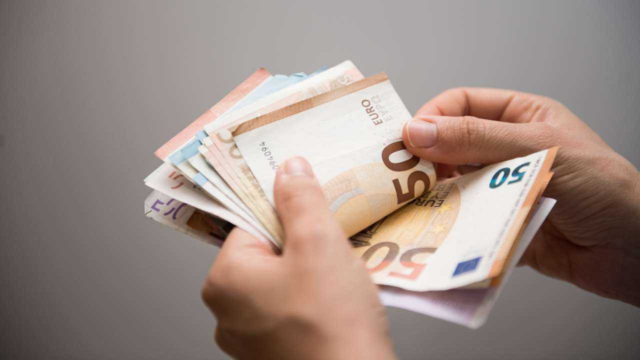Заемщик держит в руках купюры, потому что пересчитывает полученный кредит до 1000 евро